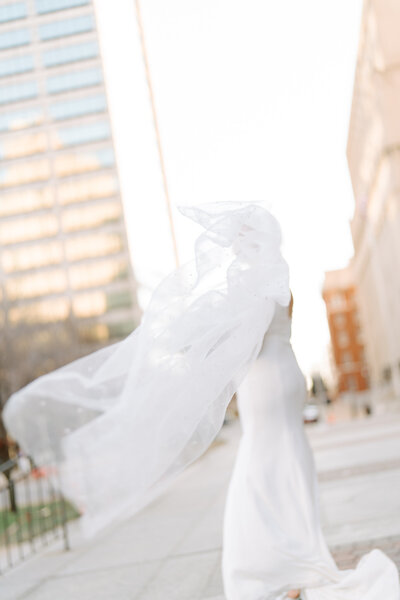 artistic photo of a bride wearing a veil that is blowing in the wind