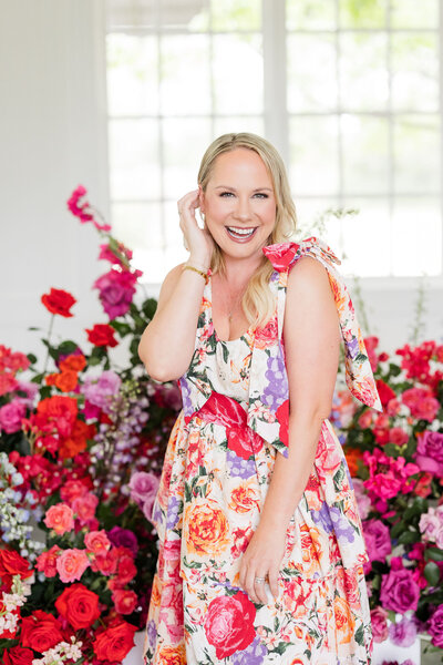 Bloom Bar founder standing joyfully in front of vibrant floral arrangements, embodying the heart-led creativity behind Austin storefront and floral design services.