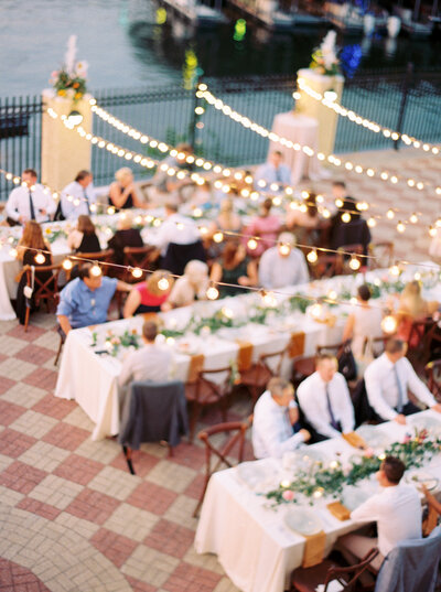 wedding guests sit under bistro lights next to Lake of the Ozarks