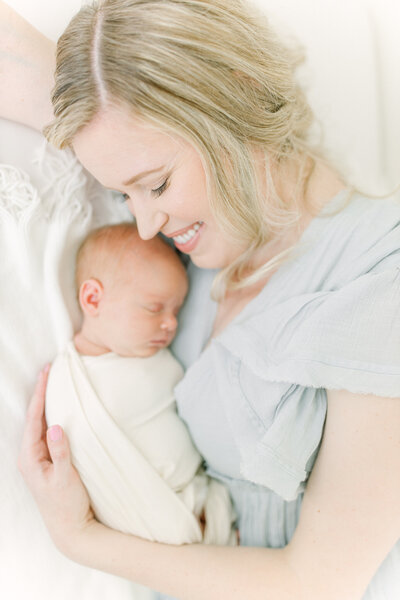 Newborn Photographer, mom smiles as she cuddles her new sleeping baby