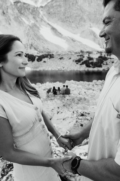 black and white photo of a couple looking at each other outdoors. Mountains in background