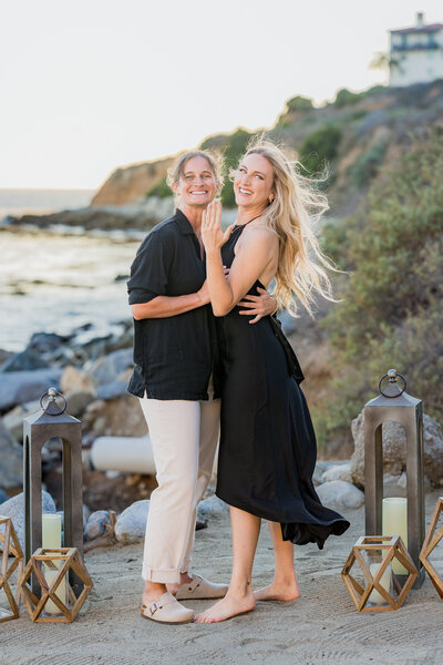 female couple celebrating their engagement on cove beach