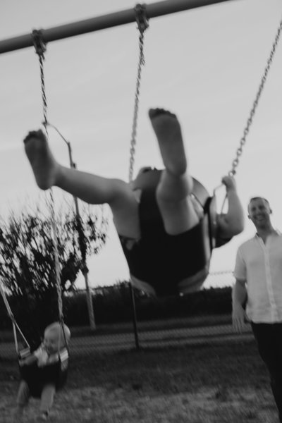 A film image of a child being pushed on a swing by their father by Boston family photographer Kelly Stevens.