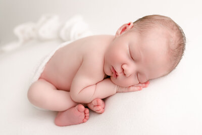 light-skinned baby sleeping with arms up on white background