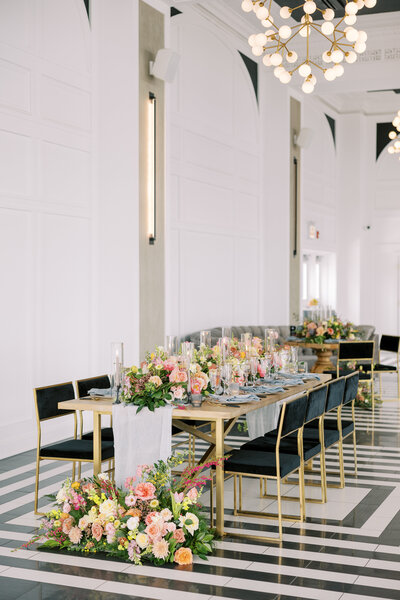 Wedding reception decor with tables, flowers and black chairs.