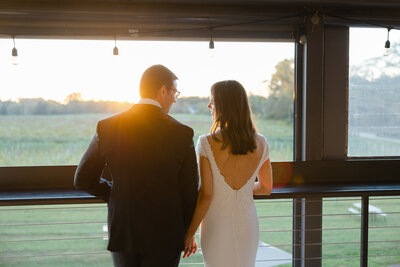 bride and groom holding hands in front of sunset