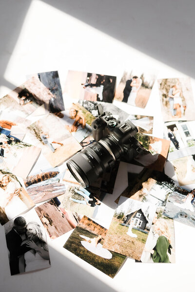 Elopement photographer displays prints on the floor with her camera and lens, showcasing stories she’s captured. 