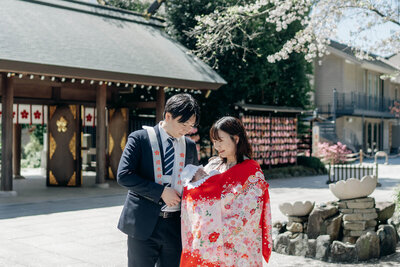お宮参り中に両親の腕の中で安心して眠る赤ちゃん