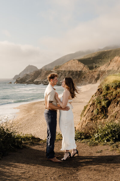 couple standing on cliff in half moon bay
