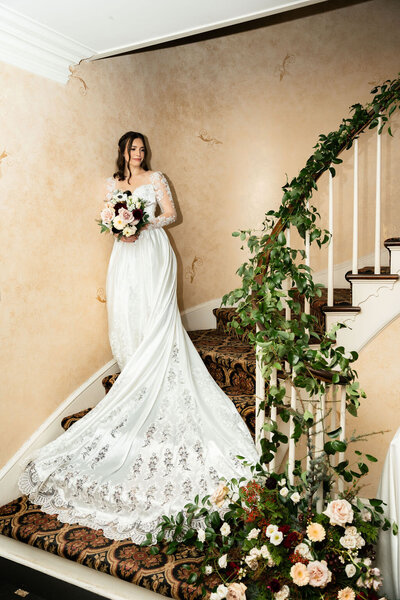 bride holding bridal bouquet and standing on staircase