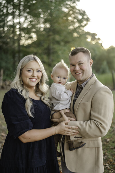 Mother and Father hold their blonde one year old during their fall family photos