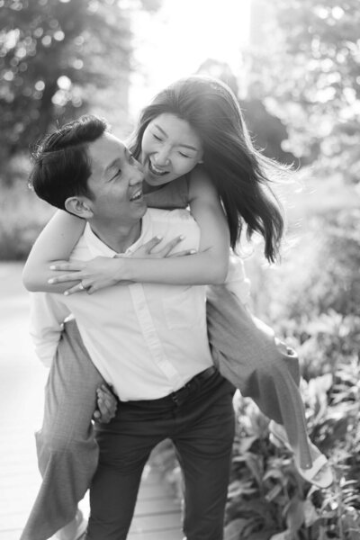 Man giving his fiancee a piggyback ride in Lincoln Park for their Chicago engagement photos