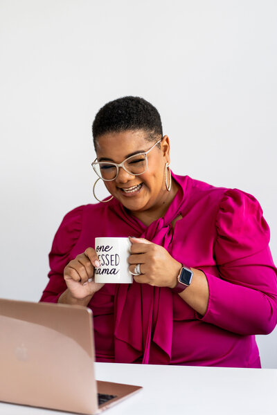 Career coach for women leaders working on her laptop while enjoying a coffee, demonstrating a balanced and productive approach to career development.