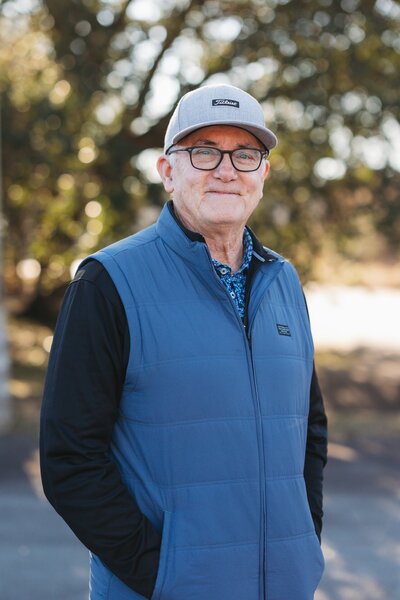 Portrait of David Munsey JR. in a gray cap and blue vest, founder of Better Lawns and Gardens and long-time landscaping professional in Little Rock.
