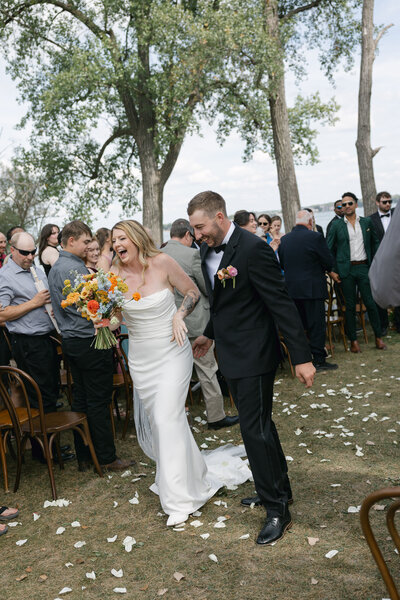 Bride and groom joyfully exiting their ceremony, surrounded by friends and family, captured by a Wisconsin wedding photographer.
