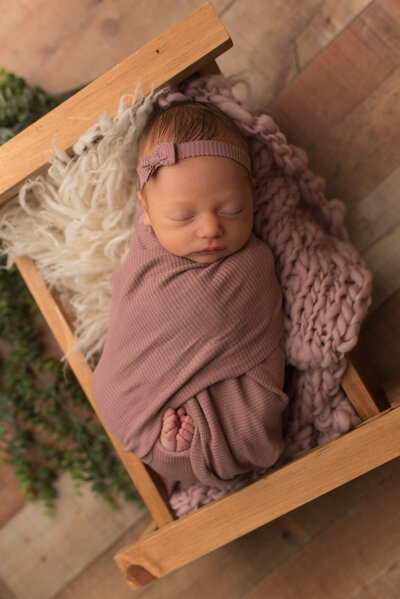 Baby girl wrapped in dusty mauve newborn set