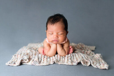 posed studio newborn session in froggy position