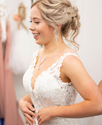 A bride smiling as she adjusts the straps of her dress
