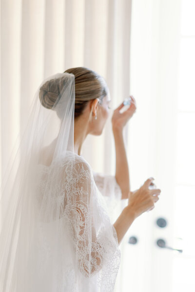 A bride applies perfume.