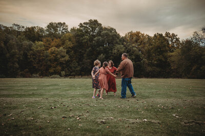 A family holding hands and dancing in a beautiful field in  Blacksburg, Virginia.