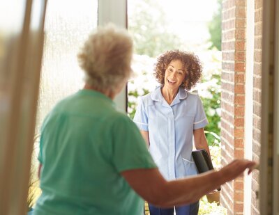 Woman opening the door to welcome clients for a personalized home coaching session on menopause.