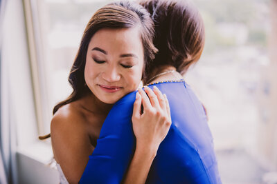 Vietnamese bride sheds a tear hugging her mom before the wedding ceremony after getting ready