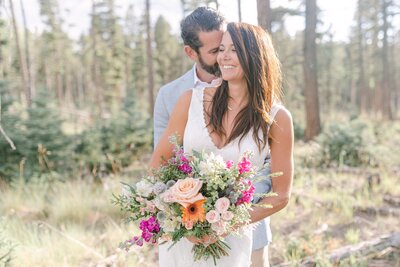 bride and groom snuggling with a beautiful bouquet of multi colored florals