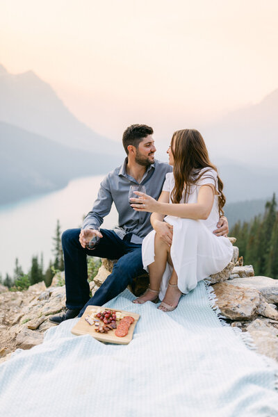Engaged couple enjoying a picnic at Peyto Lake in Banff National Park during a warm summer sunset looking at each other and sharing a relaxed romantic moment outdoors