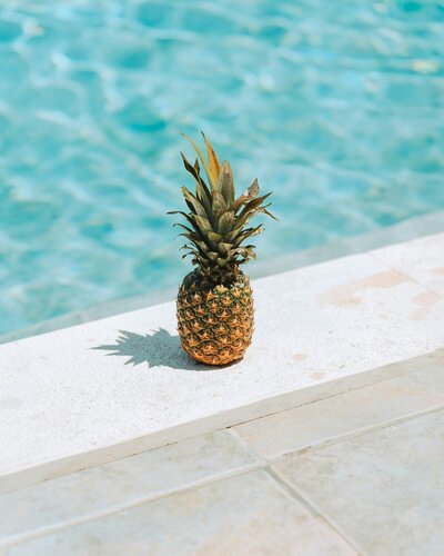 a pineapple by the pool, representing the enzymes in a pineapple that help sundamaged skin.