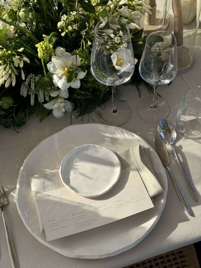 Table setting with flowers, plates, linens, and menu, representing event planning services by Perfect Thirds & Co. 