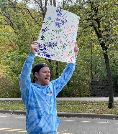 Man holding up a hand drawn sign over his head