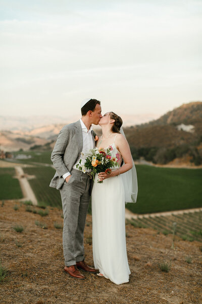Bride and groom kiss overlooking Eden Rift Vineyard