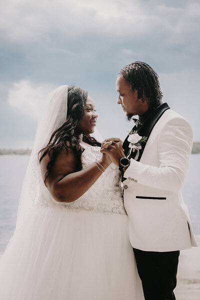 black couple on wedding day on the beach holding hands