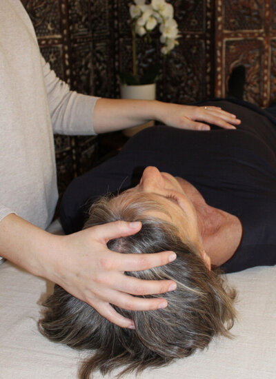 close up photo of a craniosacral treatment, with contact on the top of head and diaphragm