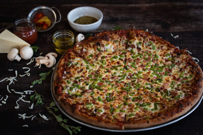 Freshly baked Redo’s pizza topped with green peppers, bacon, and cheese in Yarmouth, Nova Scotia