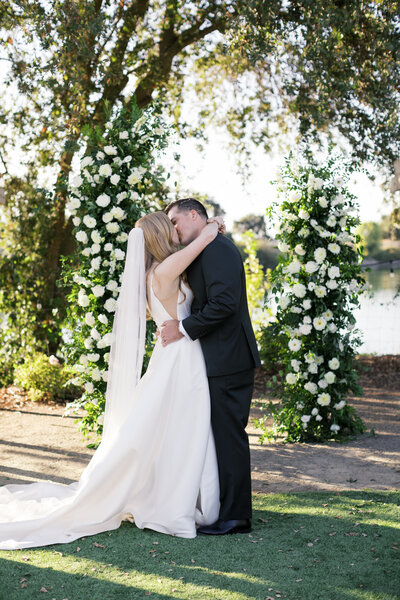 Ceremony arch bride and groom kissing at catta verdera golf course