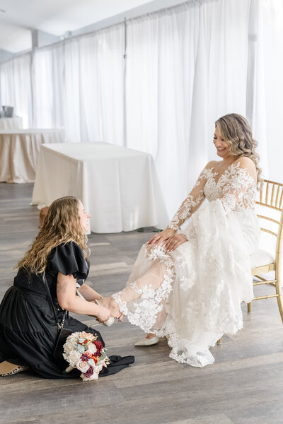 Wedding planner help bride put on shoes