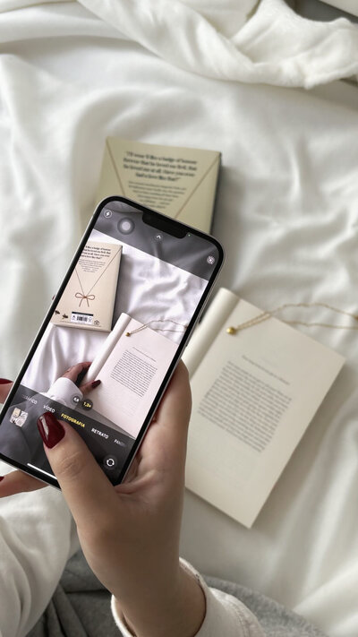 woman holding phone taking picture of a book