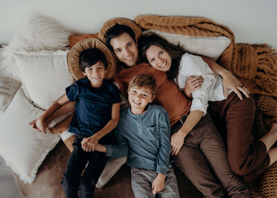 A family of four cuddle together on a bed in a photography studio in Parker Colorado.