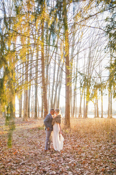 Bride and groom hug each other in the forest at white oak farm while the sun sets around the trees.