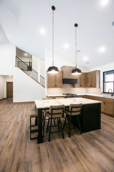 Open-concept kitchen in custom home with mixed wood cabinetry, large island, and modern finishes built by Minnesota home builders.