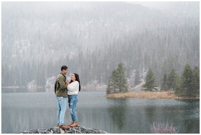 couple holding hands up high and keeping each other warm surrounded by the falling snow captured by Colorado wedding photographer