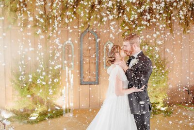 A bride and groom kiss while snow falls around them at Carolina Country Weddings.