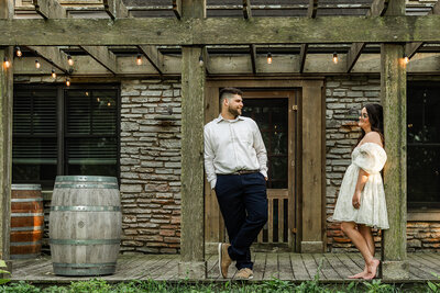 Couple standing outside a winery gazing towards each other