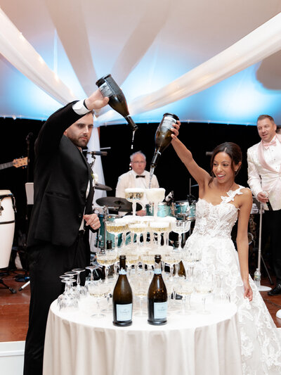 Bride and groom pouring champagne into a tower of coupe glasses