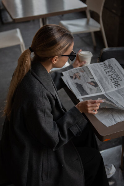 Polished woman flipping through a magazine, coffee in hand