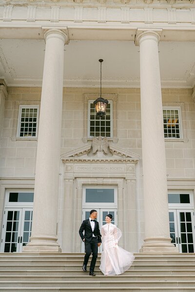 A couple walking down the stairs at the Chicago History Museum on their wedding day