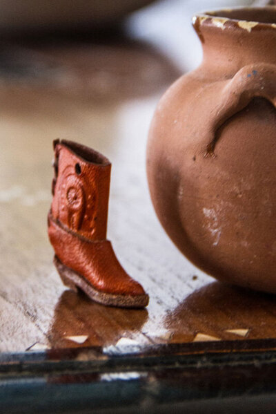 Location marketing image Gatos Trail ranch closeup tiny red cowboy boot next to ceramic bowl