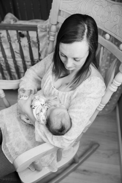 Newborn photo of baby lying in mother's arms