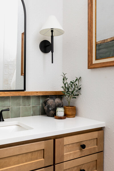 Decorative vase, candle and greenery displayed on vanity top in primary bathroom.